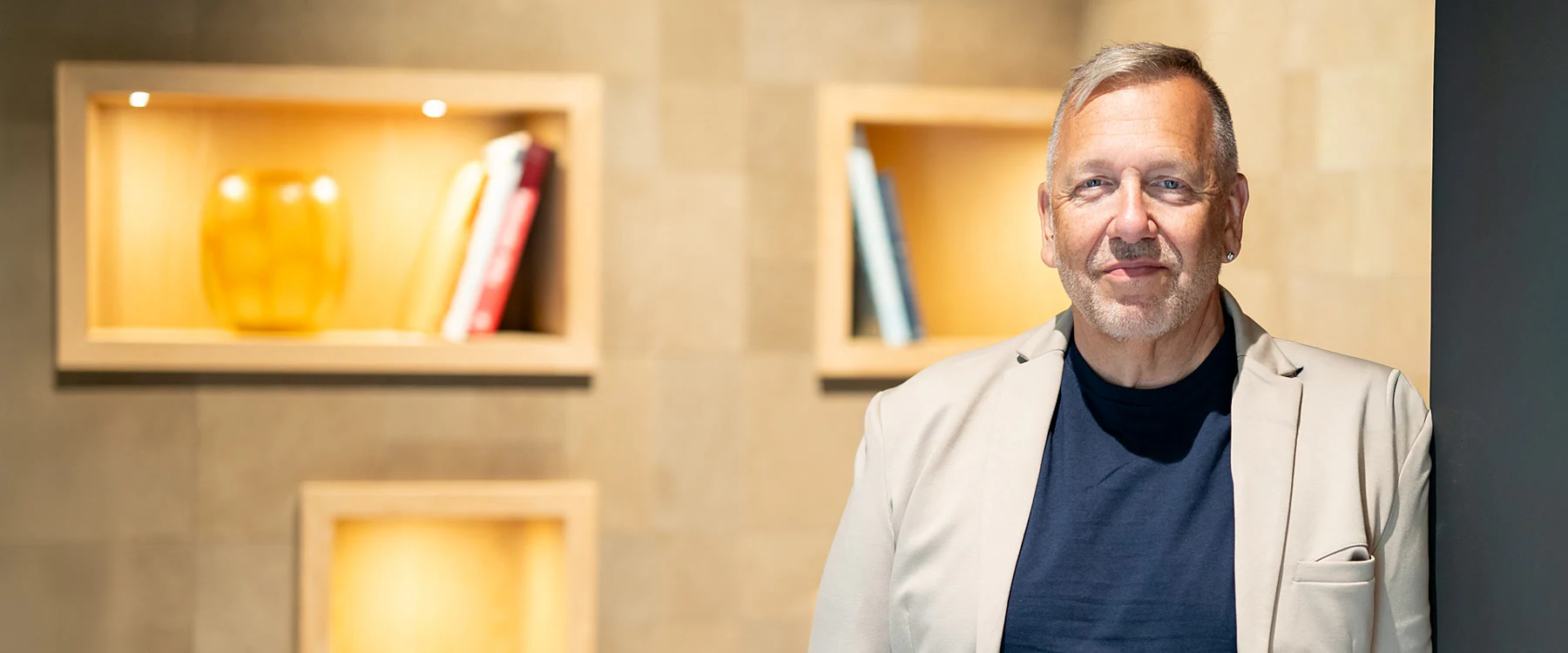 Marco Rausch vor der Wand mit den beleuchteten Nischen in den Räumen der Kanzlei
